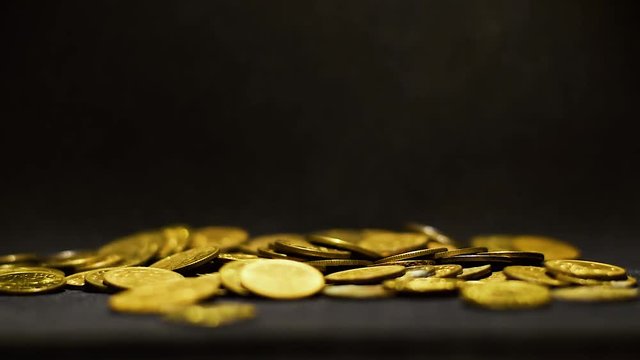 Pile of golden coins falling from the top on the black surface