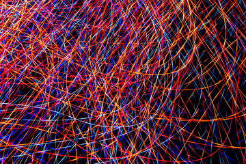 Colorful light painting abstract long exposure image with pink, blue, red and yellow lines on a black background