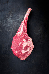 Traditional raw dry aged angus tomahawk steak as top view on an old rustic board