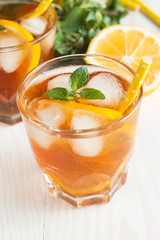 Refreshing citrus lemonade, summer drink. Ice tea with fresh lemon and mint on wooden background. Refreshment beverage concept.