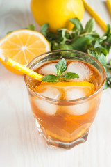 Refreshing citrus lemonade, summer drink. Ice tea with fresh lemon and mint on wooden background. Refreshment beverage concept.