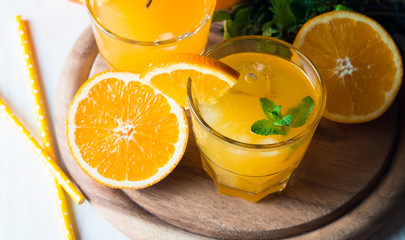 Close-up of a glass of orange juice with oranges fruits on wooden and stone background. Vitamins and minerals. Healthy drink and beverage concept.