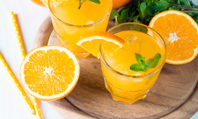 Close-up of a glass of orange juice with oranges fruits on wooden and stone background. Vitamins and minerals. Healthy drink and beverage concept.