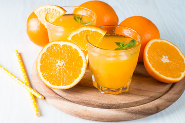 Close-up of a glass of orange juice with oranges fruits on wooden and stone background. Vitamins and minerals. Healthy drink and beverage concept.