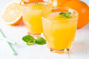 Close-up of a glass of orange juice with oranges fruits on wooden and stone background. Vitamins and minerals. Healthy drink and beverage concept.
