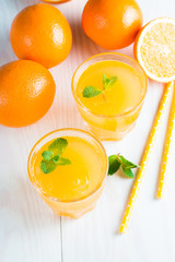 Close-up of a glass of orange juice with oranges fruits on wooden and stone background. Vitamins and minerals. Healthy drink and beverage concept.