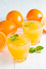 Close-up of a glass of orange juice with oranges fruits on wooden and stone background. Vitamins and minerals. Healthy drink and beverage concept.