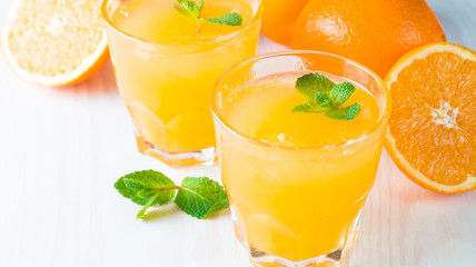 Close-up of a glass of orange juice with oranges fruits on wooden and stone background. Vitamins and minerals. Healthy drink and beverage concept.