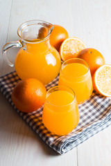 Close-up of a glass of orange juice with oranges fruits on wooden and stone background. Vitamins and minerals. Healthy drink and beverage concept.