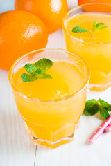 Close-up of a glass of orange juice with oranges fruits on wooden and stone background. Vitamins and minerals. Healthy drink and beverage concept.