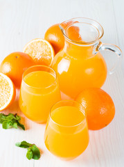 Close-up of a glass of orange juice with oranges fruits on wooden and stone background. Vitamins and minerals. Healthy drink and beverage concept.