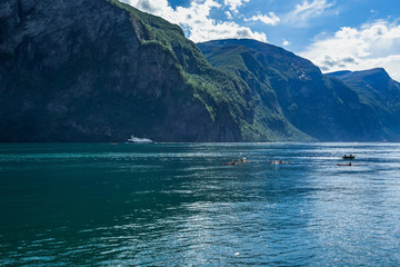 Summer view of the Geirangerfjord, with people kayaking on the fjord and a ferry boat in the background, Sunnmore, More og Romsdal, Norway