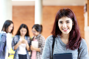 Obraz premium Headshot of young happy attractive asian student smiling and looking at camera with friends on outdoor university background. Asian woman in self future education or personalized learning concept.