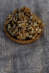 Walnuts in wooden round bowl, on sack surface