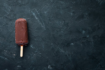 Chocolate ice cream on a stick. On a black background. Top view. Free copy space.