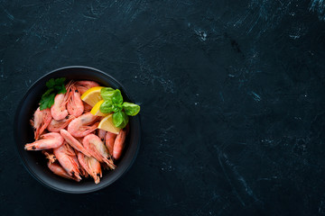 Shrimp with lemon in a plate on a black background. Top view. Free copy space.