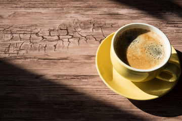flat lay  yellow cup and saucer, black coffee, in sunlight. with shadows, space for text