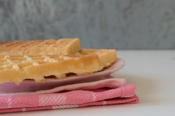 pink plate with Belgian waffles, pink tablecloth, white table