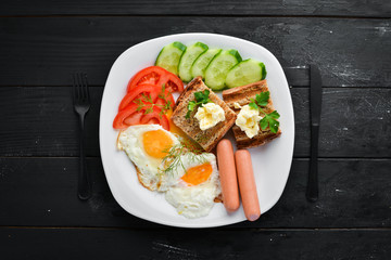 Breakfast: eggs, sausages and vegetables on the plate. Top view. Free space for your text. Rustic style.