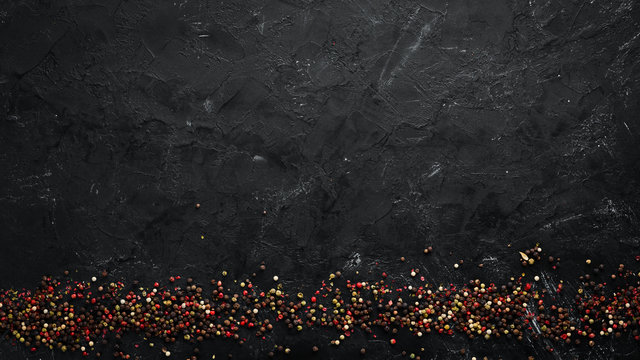 Peppers and spices on a black background. Top view. Free space for your text. Rustic style.
