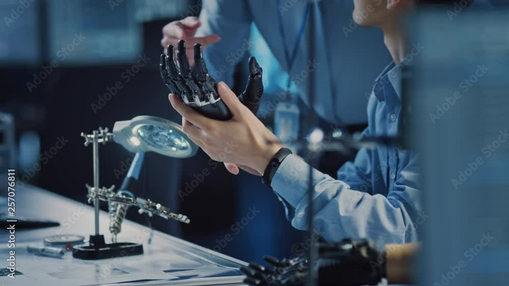 Poster technological prosthetic robot arm is tested by two professional development engineers in a high tec
