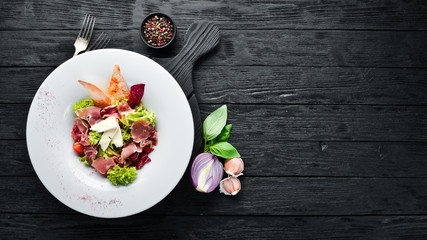 Vegetable salad with brie cheese and prosciutto. In the plate. Top view. Free space for your text. Rustic style.