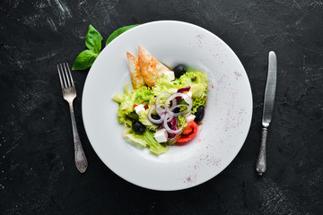 Greek salad. Vegetable salad with feta cheese, olives and cherry tomatoes. In the plate. Top view. Free space for your text. Rustic style.
