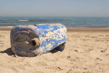 Concept of plastic pollution, global warming, recycling. Close-up on an old blue plastic can of gasoline in a beach with the blurred sea in the background. Italian beach named 