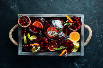 Cocktails and drinks with cranberries. Cranberries, limes, rosemary. On a black background. Top view. Free space for your text.