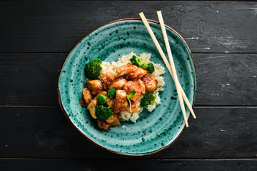 Rice with chicken fillet and broccoli. Thai cuisine. In the plate. Top view. Free space for your text. Rustic style.