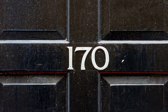 House number 170 with the one hundred and seventy in silver on the middle cross frame of a panelled wooden house door