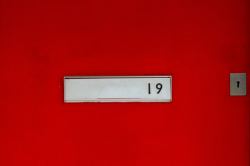 House number 19 with the nineteen in black on a silver letterbox on a red house door
