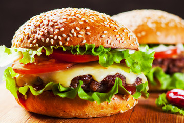 two burger with meat, cheese and vegetables on wooden board