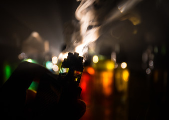 Vape concept. Electronic Cigarette vape explosion. Smoke clouds and vape liquid bottles on dark...