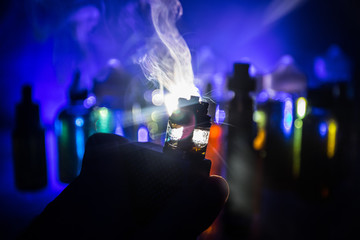 Vape concept. Electronic Cigarette vape explosion. Smoke clouds and vape liquid bottles on dark...