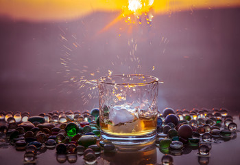 A Glass Of whiskey with ice and gold sunlight. Outdoor shot of whiskey with splash on sunset background.