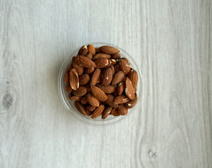 Healthy food  for background image close up almond nuts. Texture on white grey table top view. Nut on the cup plate