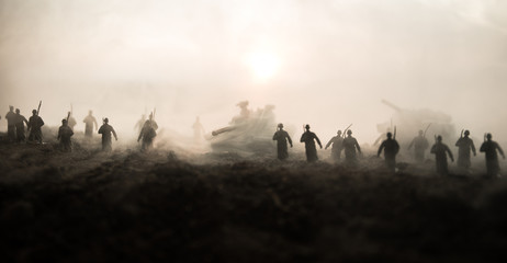 Plakat War Concept. Military silhouettes fighting scene on war fog sky background, World War Soldiers Silhouettes Below Cloudy Skyline at sunset. Attack scene. Armored vehicles.