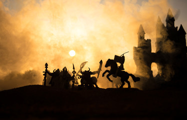 Medieval battle scene with cavalry and infantry. Silhouettes of figures as separate objects, fight between warriors on sunset foggy background.