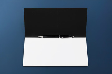 Business style. Premium accessories for writing - pen and notebook with blank page on dark blue background
