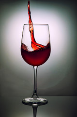 Glass of red wine with wave on grey background. Wine glass and splashing symbol design.