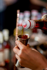 Bartender pours liquid into the jigger. Female bartender preparing cocktail in a cocktail bar