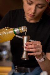 Bartender pours liquid into the jigger. Female bartender preparing cocktail in a cocktail bar