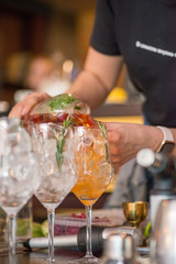 female bartender preparing aperol cocktail in a cocktail bar