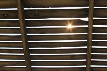 The sun's rays make their way through the dark wooden boards covering