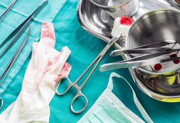 Scissors surgical with torunda soaked with blood on a tray metal in an operating theater, composition horizontal, conceptual image