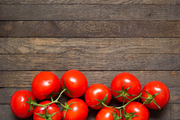 Red washed ripened tomatoes in bottom part of wooden background