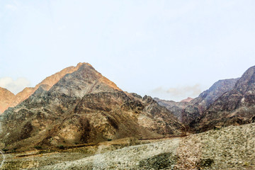 Geological landscape of Jabal Jais characterised by dry and rocky mountains, Road between mud mountains in Ras Al Khaimah, United Arab Emirates