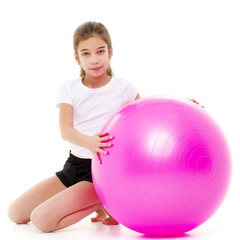 Fototapeta premium little girl doing exercises on a big ball for fitness.