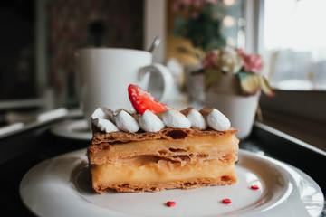 Millefeuille Napoleon with coffee in cafe. Exquisite dessert with fresh berries on white background. French Vanilla Raspberry Mille-feuille on the dish